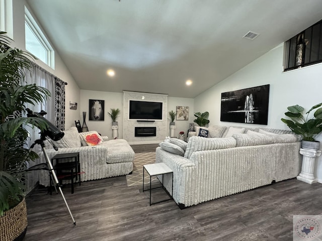 living room with dark wood-type flooring, vaulted ceiling, and a large fireplace