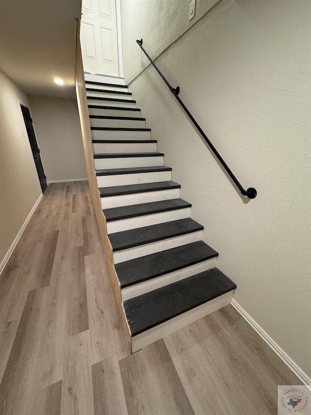 staircase with baseboards and wood finished floors