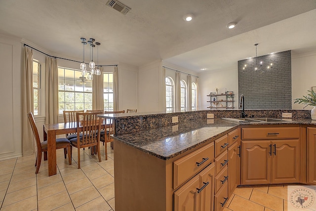 kitchen featuring dark stone counters, light tile patterned floors, hanging light fixtures, and plenty of natural light