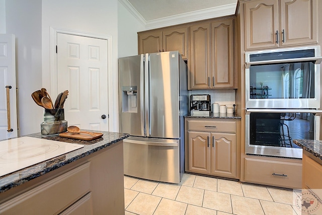 kitchen with light tile patterned floors, ornamental molding, appliances with stainless steel finishes, dark stone counters, and decorative backsplash