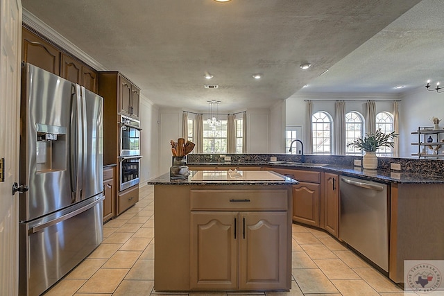 kitchen with sink, a center island, a textured ceiling, appliances with stainless steel finishes, and kitchen peninsula