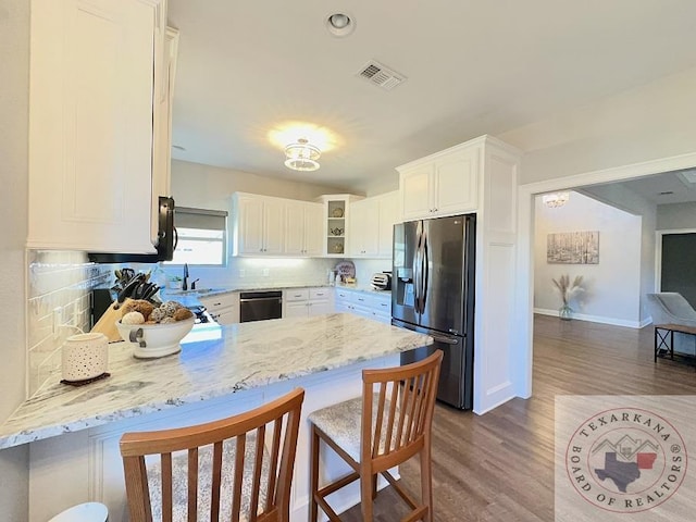 kitchen featuring decorative backsplash, white cabinets, stainless steel fridge, and kitchen peninsula