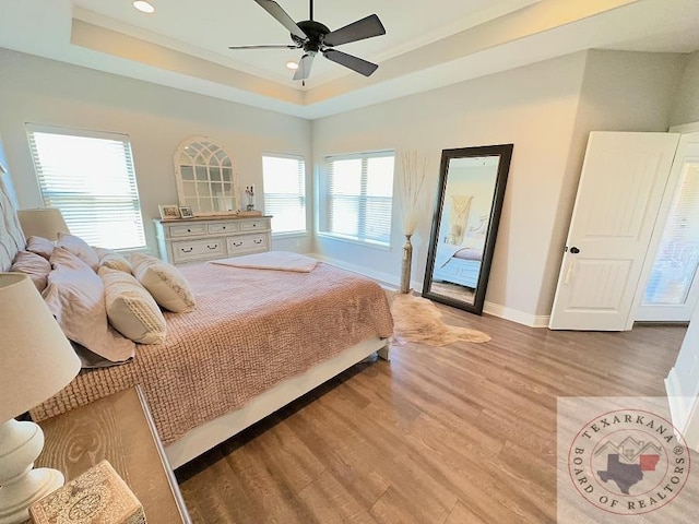 bedroom featuring ceiling fan, a tray ceiling, and light hardwood / wood-style flooring