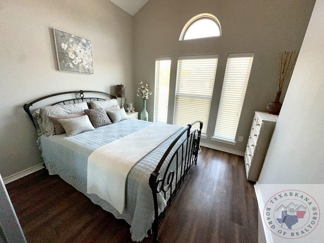 bedroom with multiple windows, dark wood-type flooring, and lofted ceiling