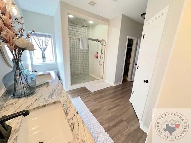 bathroom with a tile shower, hardwood / wood-style flooring, and vanity