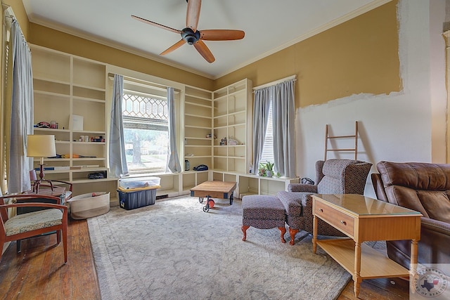 sitting room with wood-type flooring, ceiling fan, and ornamental molding