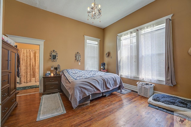 bedroom featuring a textured ceiling, dark hardwood / wood-style floors, and a notable chandelier