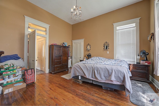 bedroom featuring dark wood-type flooring, a textured ceiling, lofted ceiling, and an inviting chandelier