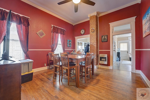 dining space featuring heating unit, a healthy amount of sunlight, ornamental molding, and wood-type flooring