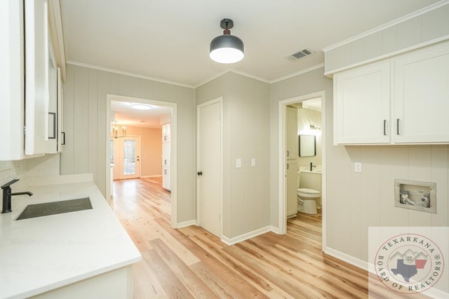 kitchen featuring sink, white cabinetry, ornamental molding, and light hardwood / wood-style floors