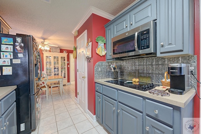 kitchen with a textured ceiling, stainless steel appliances, decorative backsplash, light tile patterned flooring, and crown molding