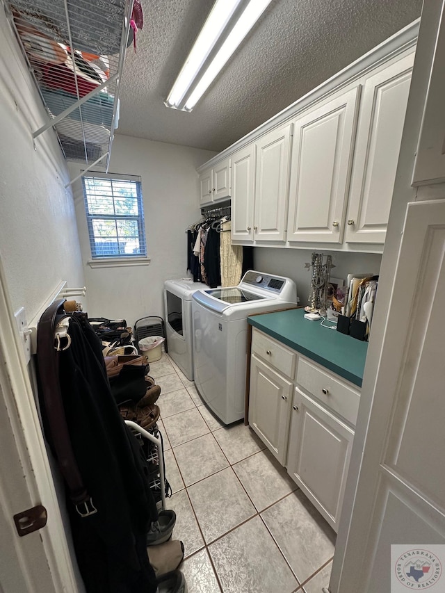 washroom featuring separate washer and dryer, a textured ceiling, light tile patterned floors, and cabinets