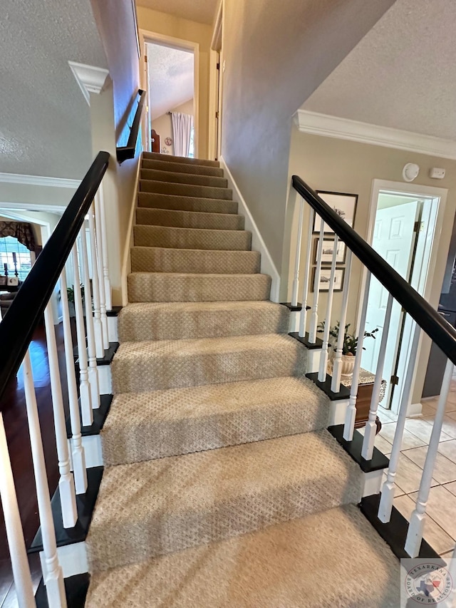 stairway with crown molding, a textured ceiling, and tile patterned floors