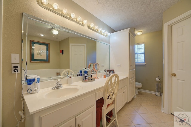 bathroom with vanity, toilet, a textured ceiling, and tile patterned flooring