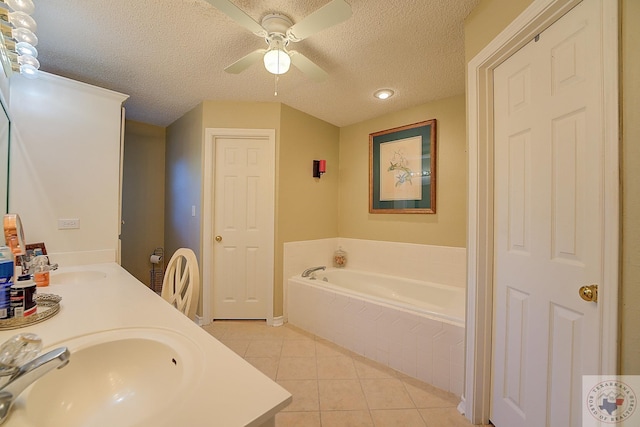 bathroom with a textured ceiling, tiled tub, tile patterned floors, vanity, and ceiling fan