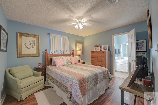 bedroom featuring dark wood-type flooring, a textured ceiling, ensuite bath, and ceiling fan