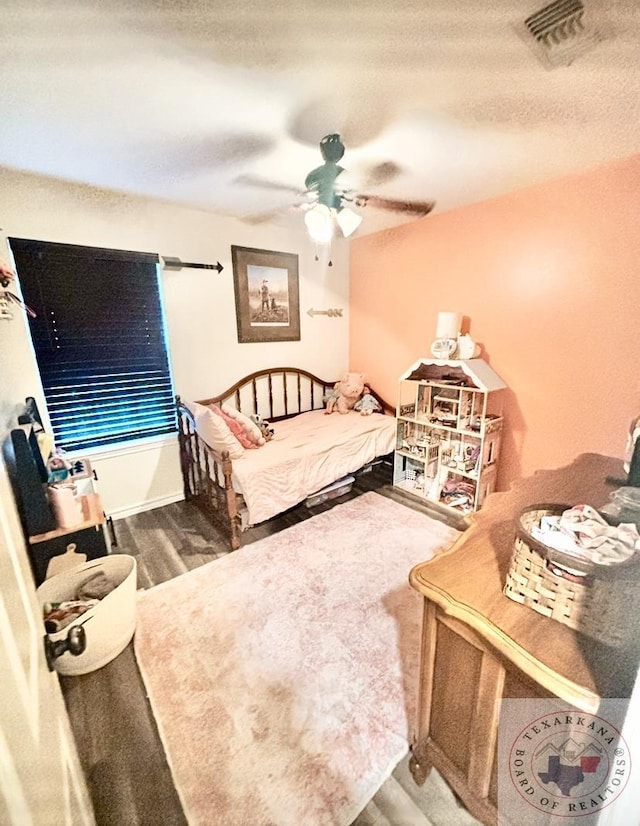 bedroom with a textured ceiling, wood-type flooring, and ceiling fan