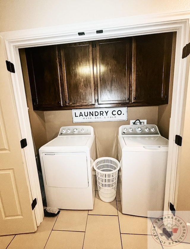 washroom featuring washer and dryer, cabinets, and light tile patterned flooring