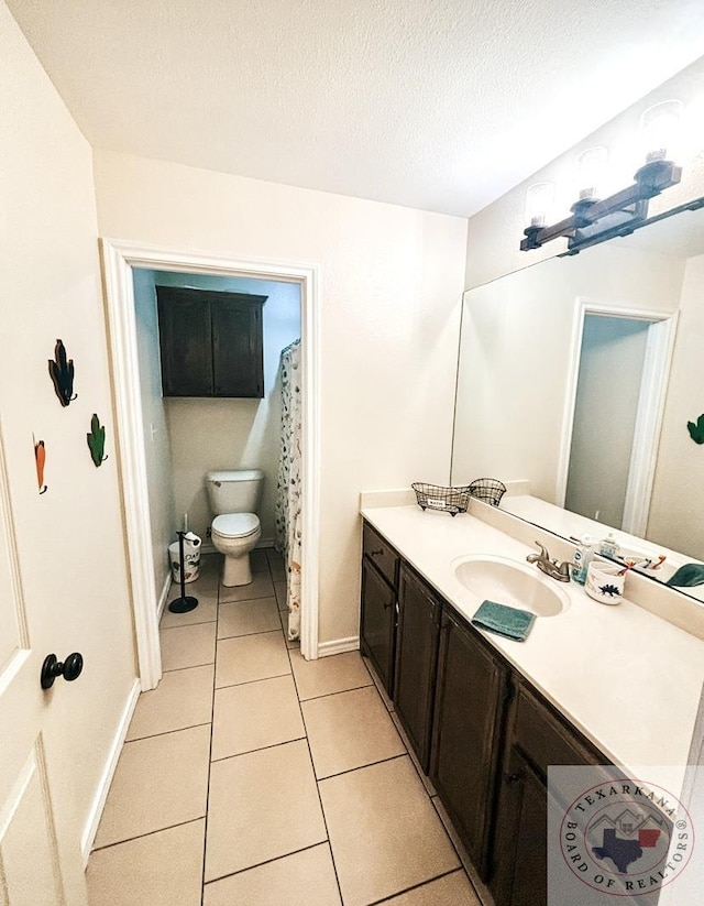 bathroom featuring a textured ceiling, toilet, tile patterned floors, and vanity