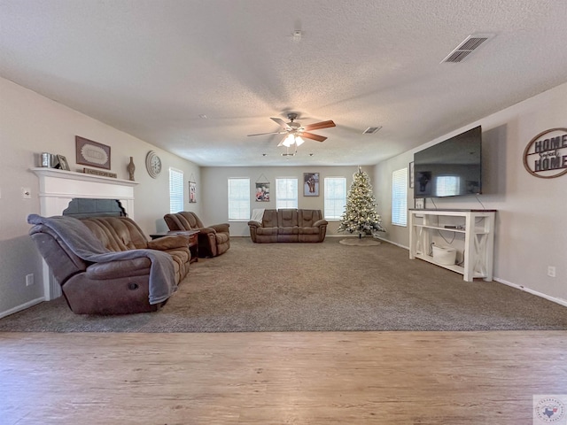 living room with ceiling fan, a textured ceiling, and hardwood / wood-style floors