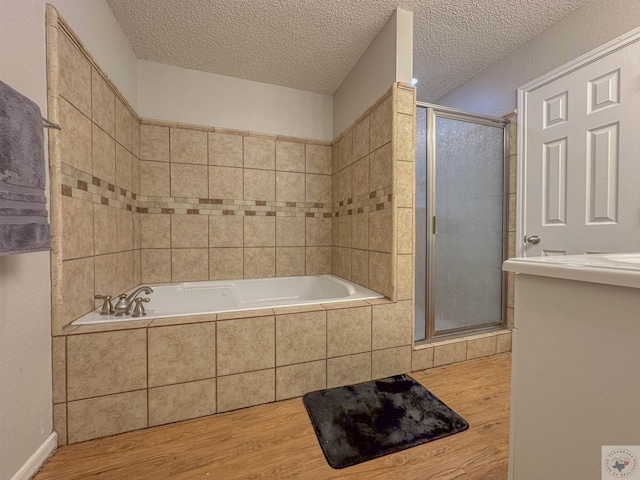 bathroom with hardwood / wood-style floors, separate shower and tub, and a textured ceiling