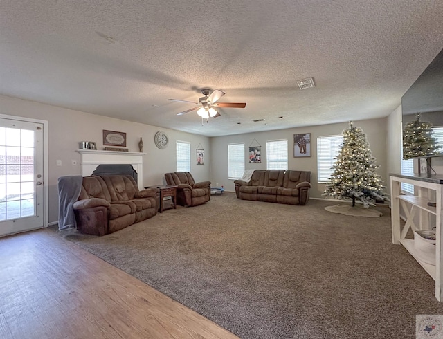 carpeted living room featuring a textured ceiling and ceiling fan