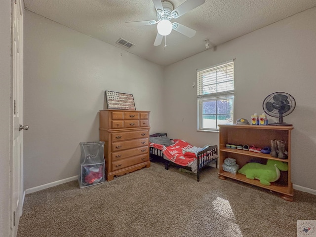 carpeted bedroom featuring ceiling fan and a textured ceiling