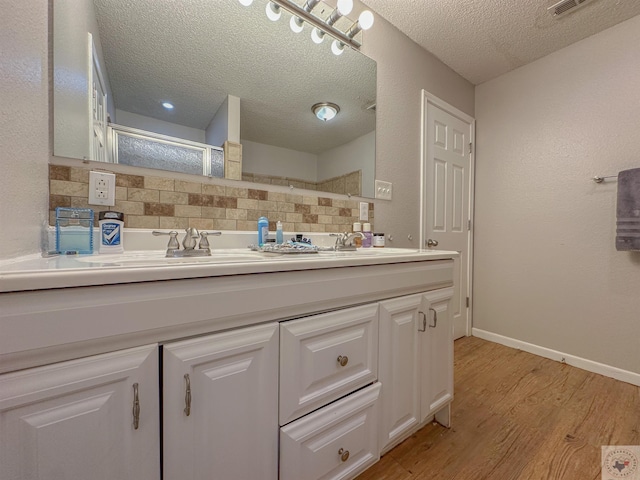 bathroom featuring vanity, hardwood / wood-style floors, tasteful backsplash, and a textured ceiling