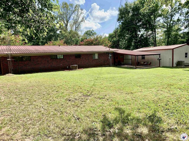 308 Eleanor St, Atlanta, TX 75551 - rear view of house with a lawn, a metal roof, and brick siding
