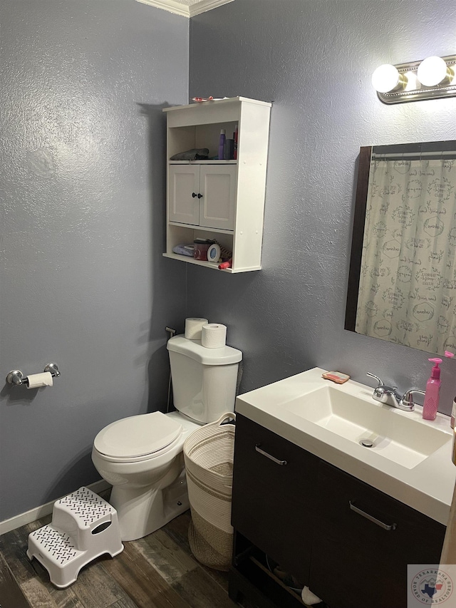 bathroom with vanity, toilet, hardwood / wood-style floors, and crown molding