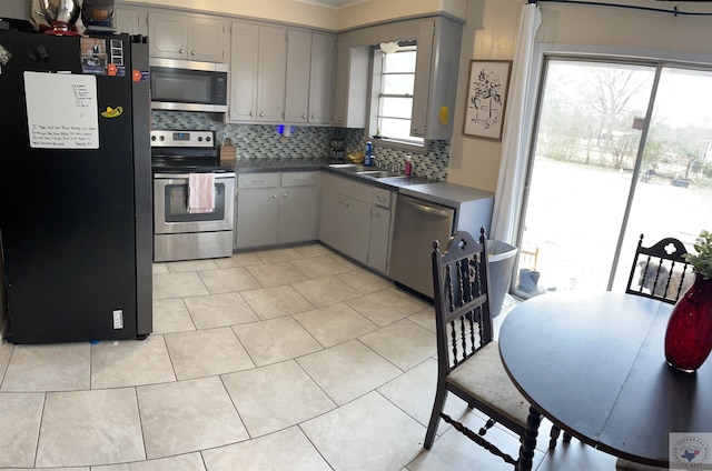 kitchen with sink, stainless steel appliances, light tile patterned flooring, and gray cabinets