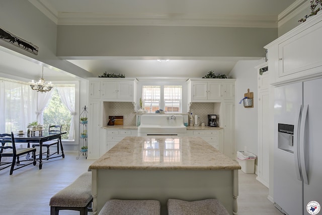 501 Main St, Texarkana, TX 75501 - kitchen with white cabinets, a kitchen breakfast bar, a notable chandelier, and refrigerator with ice dispenser