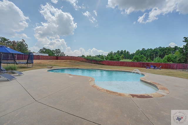 view of swimming pool featuring a trampoline, a patio area, pool water feature, and a lawn