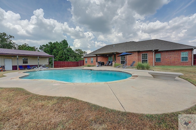 view of swimming pool featuring a diving board, a patio area, and a yard