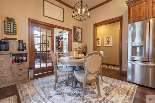 dining area with dark wood-type flooring, a notable chandelier, and ornamental molding