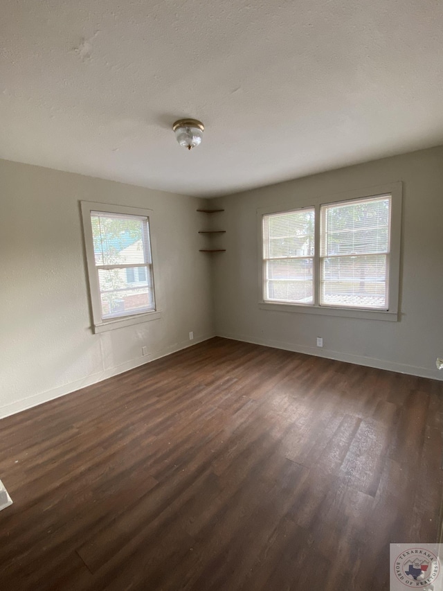 empty room with a textured ceiling and dark hardwood / wood-style flooring