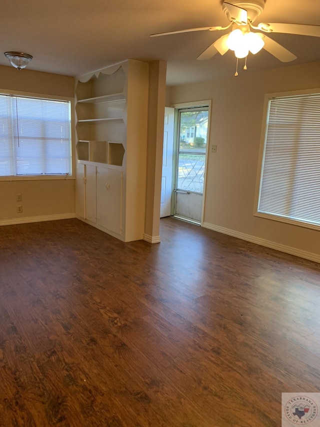 unfurnished living room with ceiling fan, built in shelves, and dark hardwood / wood-style flooring