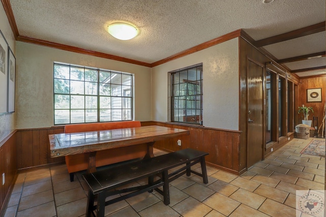 tiled dining room featuring a textured ceiling, crown molding, and wooden walls