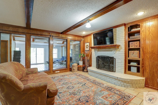 tiled living room with built in features, beam ceiling, a brick fireplace, a textured ceiling, and wooden walls