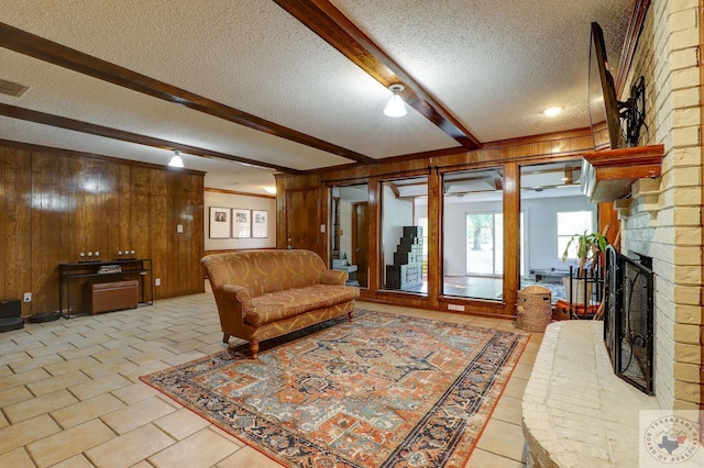 tiled living room featuring a textured ceiling, wooden walls, beamed ceiling, and a fireplace