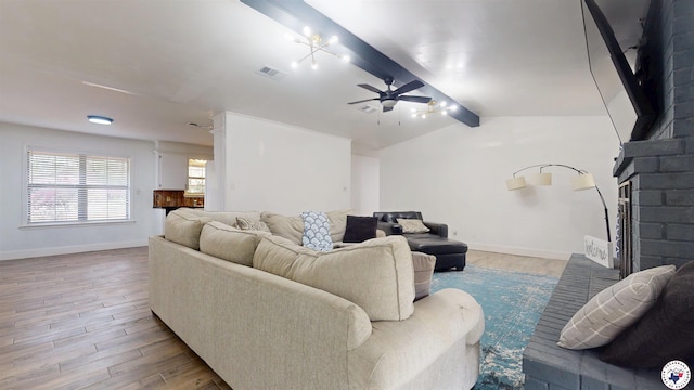living room featuring a ceiling fan, a brick fireplace, lofted ceiling with beams, and wood finished floors