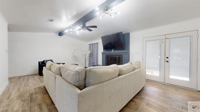 living room featuring light hardwood / wood-style floors, a fireplace, french doors, vaulted ceiling with beams, and ceiling fan with notable chandelier