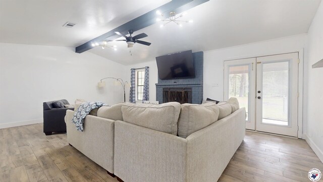 living area with lofted ceiling with beams, a wealth of natural light, visible vents, and hardwood / wood-style flooring
