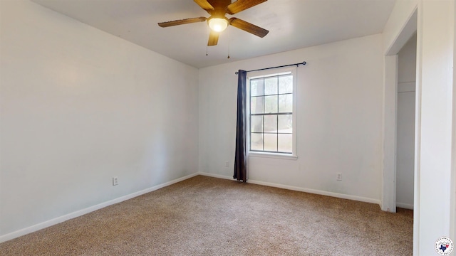 carpeted empty room with baseboards and a ceiling fan