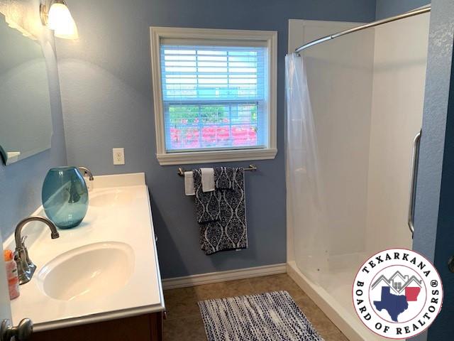 full bathroom featuring double vanity, a sink, tile patterned flooring, and a shower with curtain
