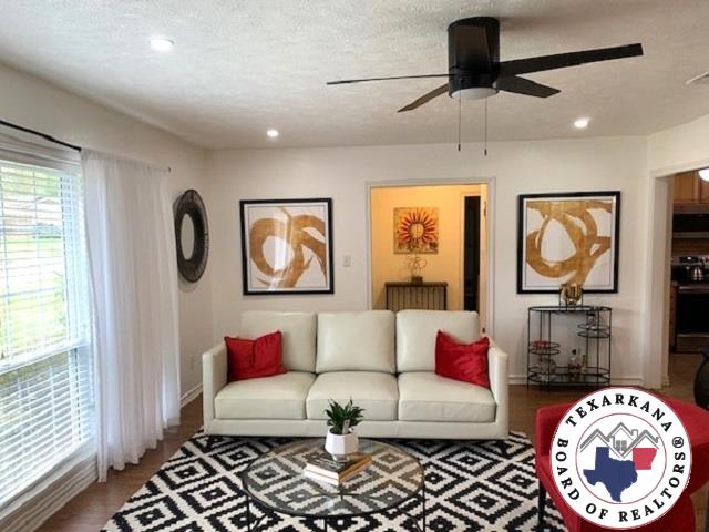 living room featuring baseboards, a ceiling fan, recessed lighting, and a textured ceiling