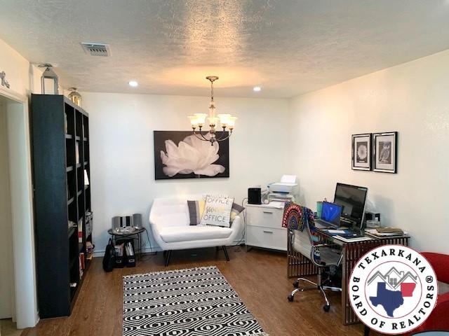 office area featuring an inviting chandelier, a textured ceiling, wood finished floors, and visible vents