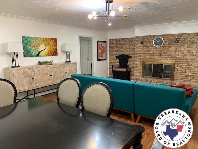 playroom featuring crown molding, an inviting chandelier, wood finished floors, a fireplace, and a textured ceiling