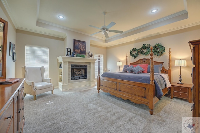 carpeted bedroom with ceiling fan, a tray ceiling, and ornamental molding