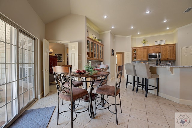 dining room featuring light tile patterned flooring, vaulted ceiling, and ornamental molding